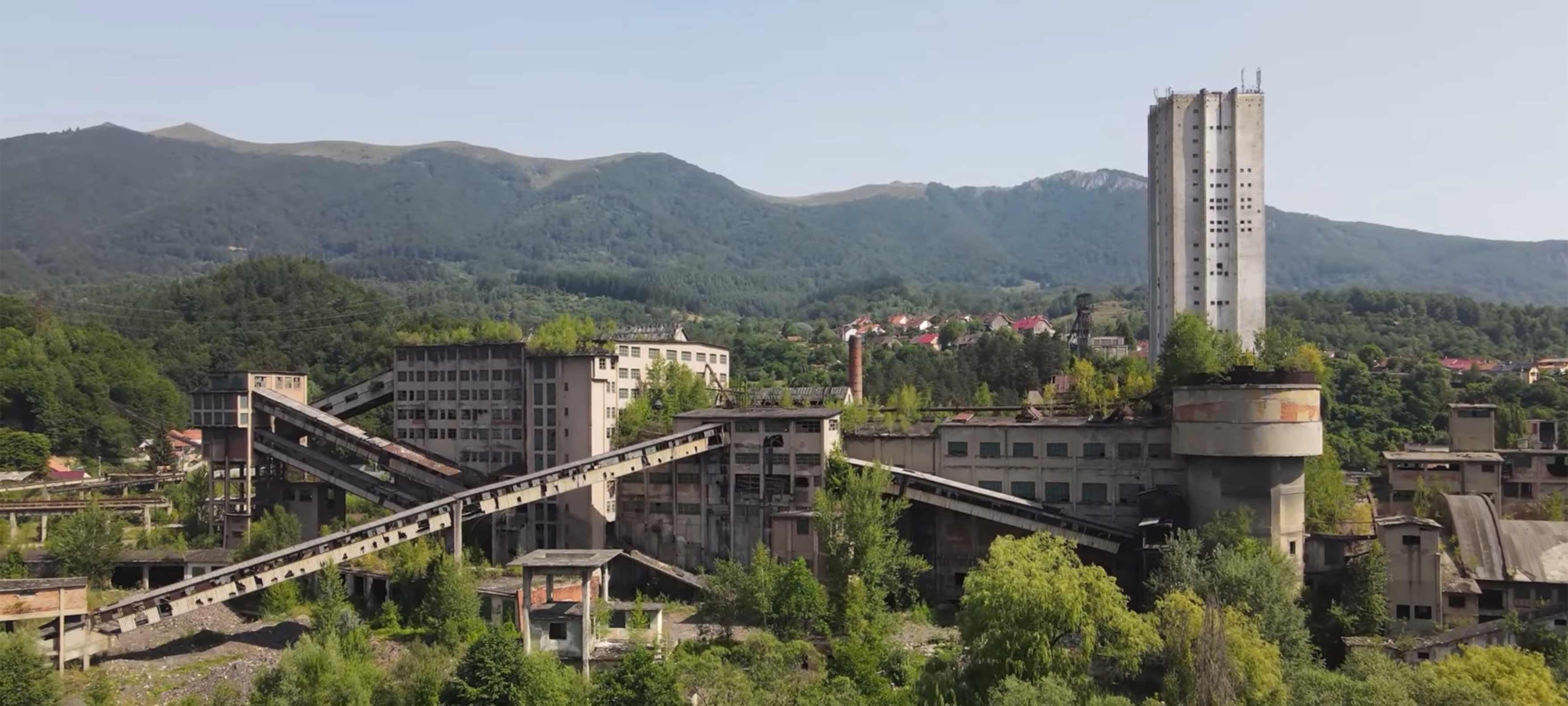 Situl minier abandonat din Lupeni, văzut de sus, cu munții Văii Jiului în fundal.